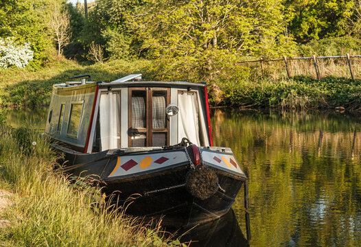 a decorated boat moored on a sunny spring evening on the Leeds and Liverpool Canal between Hirst Lock and the world heritage site Victorian model village of Saltaire