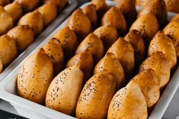 Golden baked buns with poppy seed filling arranged in rows on a table