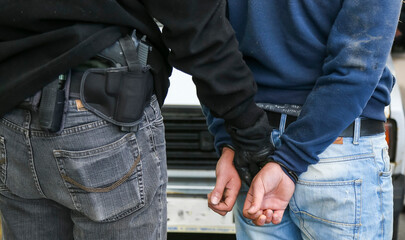 Police officer arrests a suspect in a nearby urban location during daylight hours