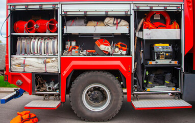 Detailed view of emergency response equipment organized in a fire truck at a station during daytime