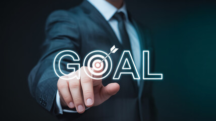 A professional business photo of a hand in a dark suit touching a glowing holographic GOAL text with a target icon.