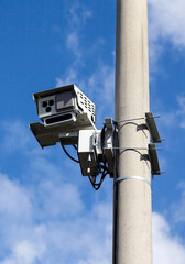 Security camera mounted on a utility pole against a clear blue sky in a suburban area during daylight hours