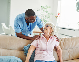 Doctor or nurse caregiver with senior woman talking and having fun at home or nursing home
