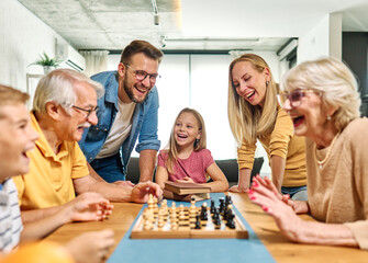 Portrait of a three generation family, grandparents, parents and children playing chess and having fun at home