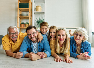 Portrait of a three generation family, grandparents, parents and children sitting on floor  and...
