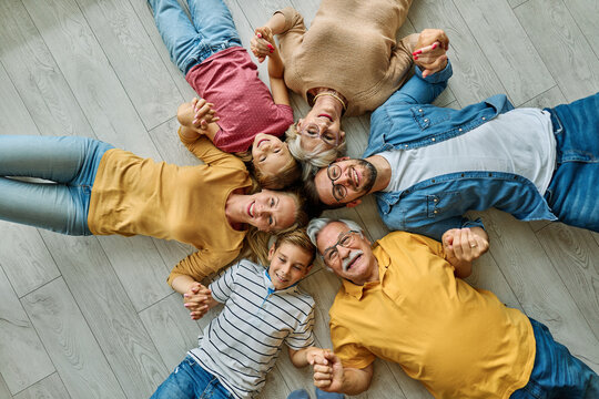 Portrait of a three generation family, grandparents, parents and children sitting on floor  and having fun posing at home - Powered by Adobe