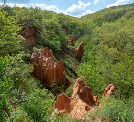Pits valley. Unique red rock formations emerge from the lush greenery in Puy de Dome, showcasing the beauty of Boudes in the Valley of the Saints. Puy de Dome. Auvergne Rhone Alpes. France