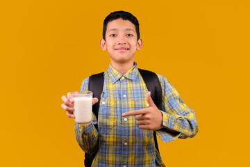 Cheerful Young Asian Student Boy Pointing While Holding Milk On Glass
