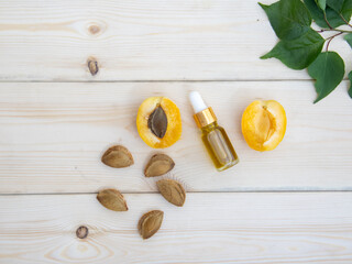 Serum or oil in a glass bottle with fresh apricots on a wooden background. A mock-up of a brand of natural cosmetics.