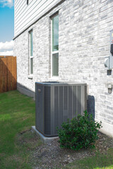 Outdoor HVAC unit and wall mounted electrical boxes installed alongside modern brick home, clean...