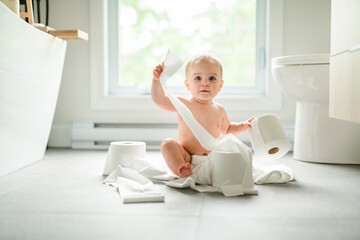 Toddler ripping up toilet paper in bathroom