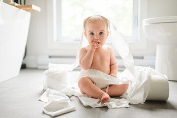 Toddler ripping up toilet paper in bathroom