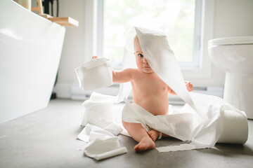 Toddler ripping up toilet paper in bathroom