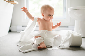 Toddler ripping up toilet paper in bathroom