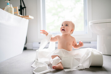 Toddler ripping up toilet paper in bathroom