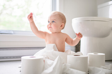 Toddler ripping up toilet paper in bathroom