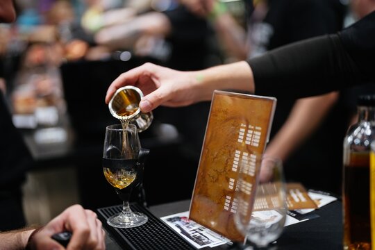 Bartender skillfully pours whiskey into a glass at a lively event