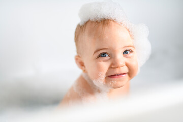 Cute little child bathing in tub at home