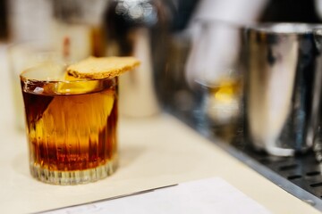 Craft cocktail garnished with a biscuit on a bar counter in an upscale setting
