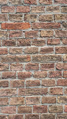 A full-frame, textured close-up reveals an old, rustic brick wall with weathered, varied-colored bricks and visible mortar lines, forming a classic pattern