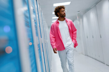 It technician walking in data center corridor checking servers