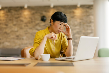 Woman experiencing office fatigue while working on a laptop at a desk