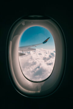 Fototapeta View of clouds and airplane wing through a window during flight