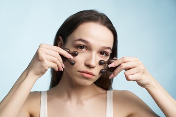 Woman performing facial massage with massage tools in bright setting