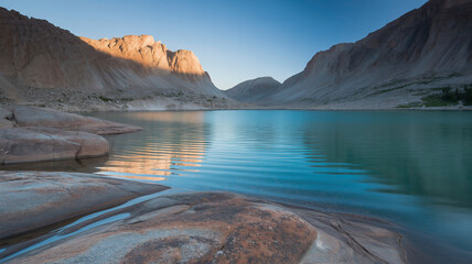 A dramatic landscape photograph captures a
turquoise mountain lake nestled between imposing granite cliffs. 