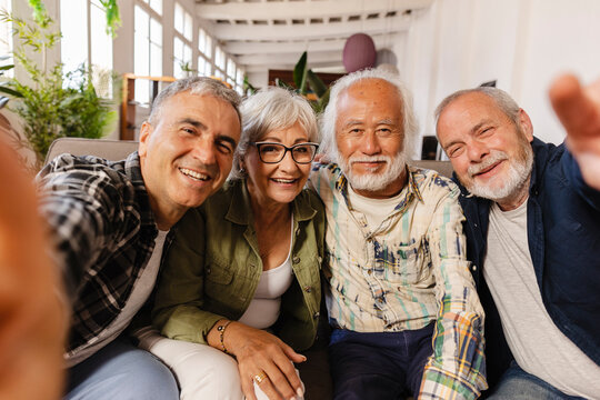 Group of happy senior friends taking selfie on sofa