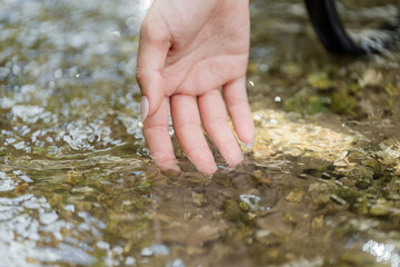 Nature Connection. Hand gently touching the clear water in a serene outdoor setting.