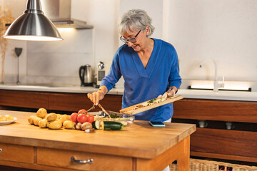 Senior woman preparing healthy meal with vegetables in modern kitchen