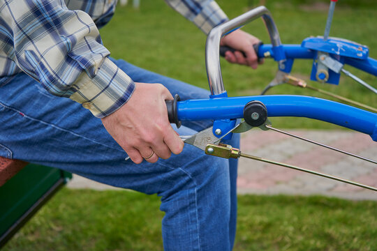 man holding the handle of a walk-behind tractor, close-up of a hand squeezing the handle to unlock the wheels of a walk-behind tractor to turn, control of a walk-behind tractor