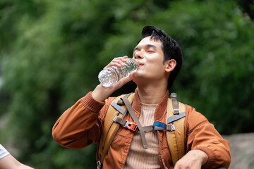 Outdoor Adventure and Hydration. Young man drinking water during a nature hike.