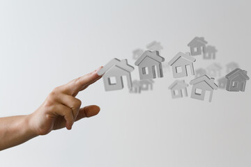 Conceptual image: hand choosing a house, ideal for real estate, property, and home buying websites.