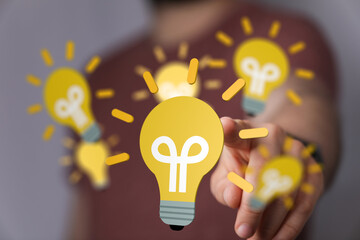 Stock photo of a person interacting with digital lightbulb icons, representing innovation and...