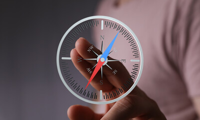 Close-up of a hand interacting with a digital compass, showing navigation and direction.
