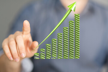 Hand pointing at upward green arrow graph.  Illustrates growth, success, and financial prosperity.