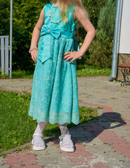 child girl in a long turquoise dress, little girl standing in the yard in a festive dress
