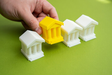 Hand choosing yellow bank building. Choosing the best banking for business and investment. Services, trust, capital strategy. Creditworthiness, economic decisions.