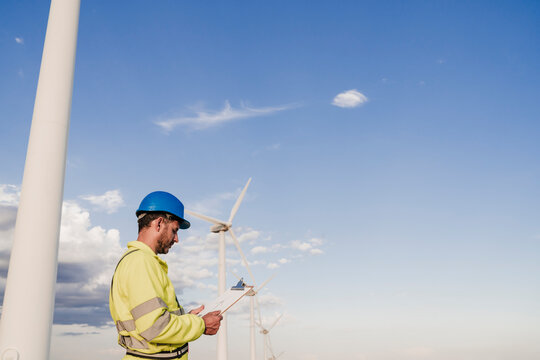 Engineer wearing hardhat working by wind turbines