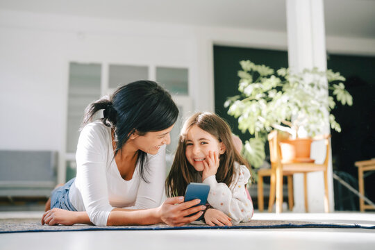 Mother and daughter spending quality time together indoors with a smartphone