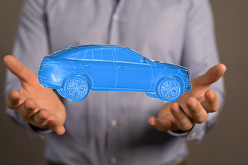 A man's hands gently cradle a digital rendering of a modern blue car, representing automotive...