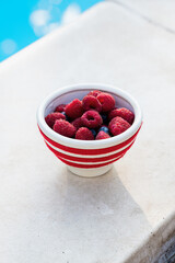 Close up of a bowl of fresh mixed berries by the pool, a healthy summer snack