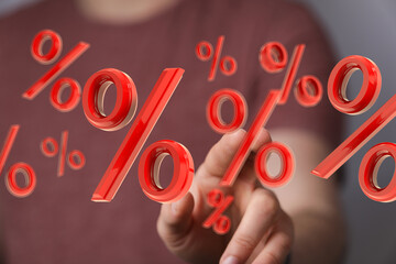 Person touching floating percentage signs, illustrating discounts, interest rates, or sales.