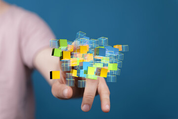 Abstract image of hand interacting with colorful digital cubes, representing data, technology,...