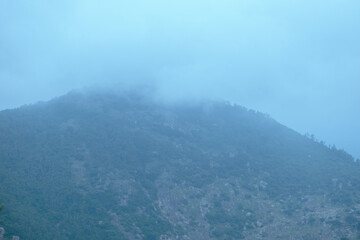 A mist-covered mountain landscape during monsoon season in Nandi Hills, India.