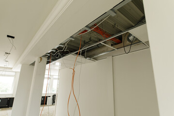 Image of unfinished ceiling showing exposed wires, metal framework, and electrical conduit. Ideal for construction or renovation projects.