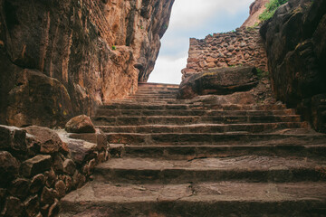 Ancient stone steps carved into reddish rock, leading through a narrow rocky canyon passage.