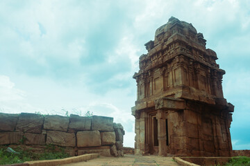 A serene walkway leads to a small ancient temple  under dramatic cloudy sky at Badami, Karntaka,...